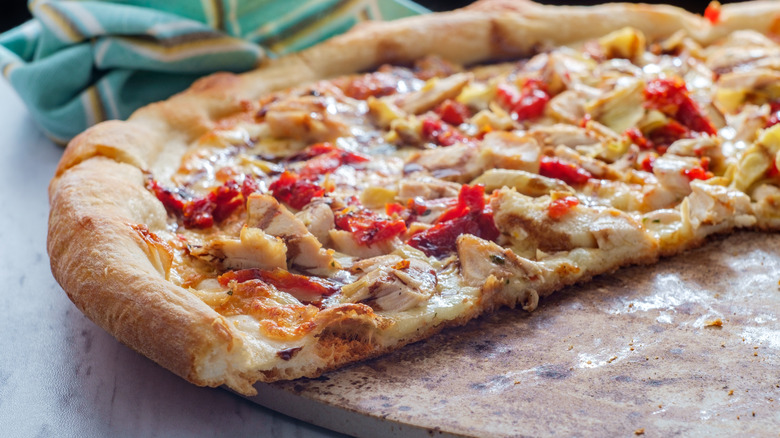 Closeup of veggie and chicken pizza on a pizza stone